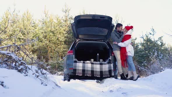 Young Couple a Man and a Woman Hugging and Kissing Near the Car in a Winter