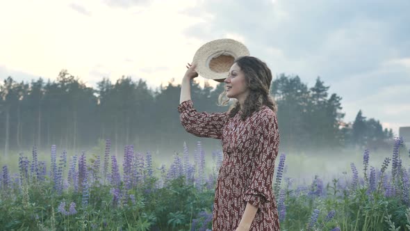 Positive Woman Takes Off and Throws Hat Near Lupin Field