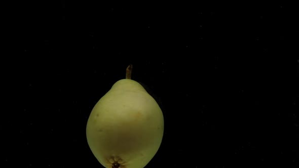 Slow Motion One Pear Spinning Falling Into Transparent Water on Black Background