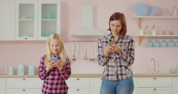 Young 30s Mother and Pre Teen Daughter Surfing Social Media, Texting Messages Using Mobile Phones