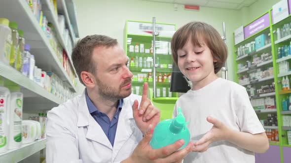 Mature Male Pharmacist Talking To a Little Boy at Drugstore