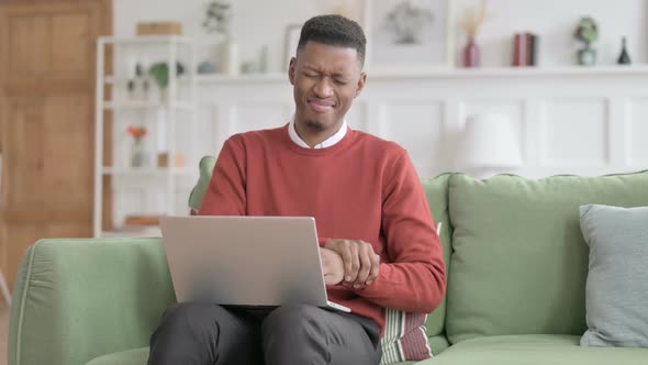 African Man with Laptop having Wrist Pain on Sofa