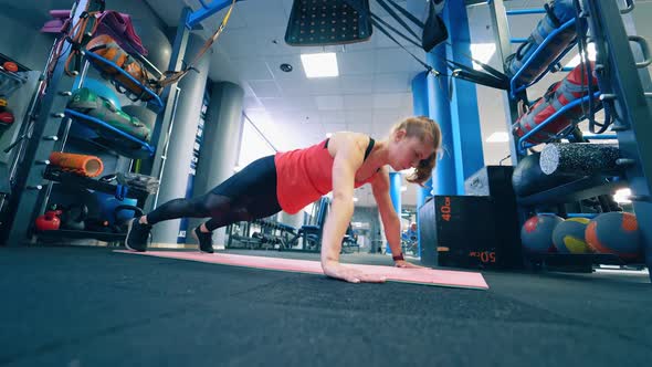 Athletic woman does push-ups as part of workout.