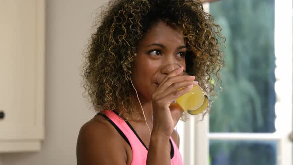 Happy woman drinking juice while listening to music