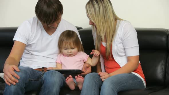 Family with young child playing with digital tablet