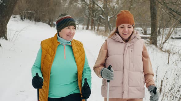 Happy Aged Woman with Daughter Practice Nordic Walking in Winter in Nature