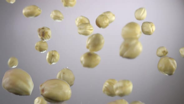 Closeup of Freshly Peeled Hazelnuts Bouncing and Spinning on White Background