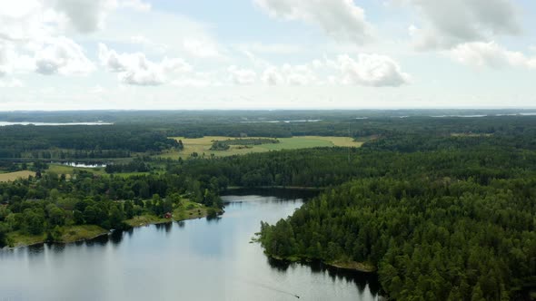 Aerial view overlooking a calm lake, forest and the countryside, on a warm, partly sunny day, in Ink