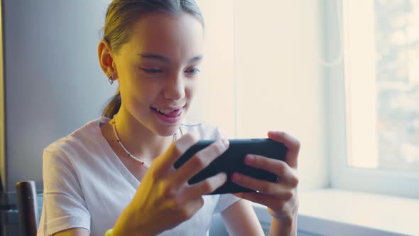 Teenager Girl Playing Video Game Touching Smartphone Screen  She Having Fun at Home