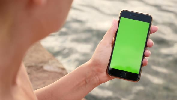 NICE, FRANCE - JULY 2017 Woman with green screen display modern phone by the sea slow-mo video