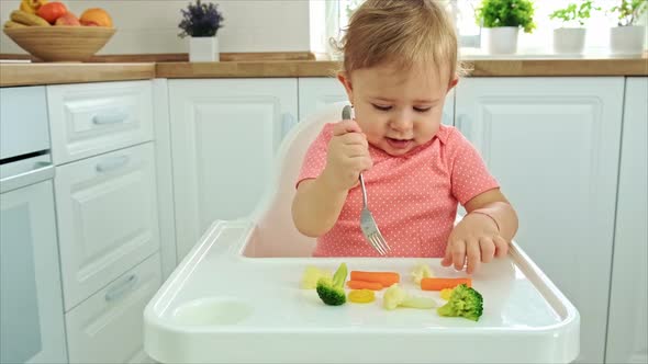 Baby Eats Vegetables on a Chair