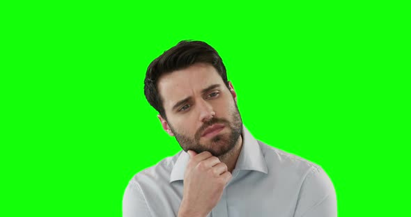 Thoughtful man standing against green screen