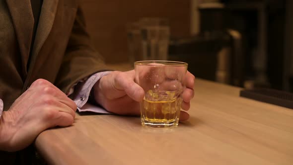 Close-up of the hand of a visitor who catches a sliding glass of whiskey