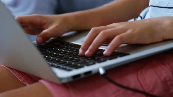 Mid section of boy using laptop in living room