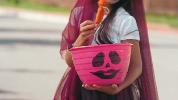 Unrecognizable Girl Looking at Candy on Halloween