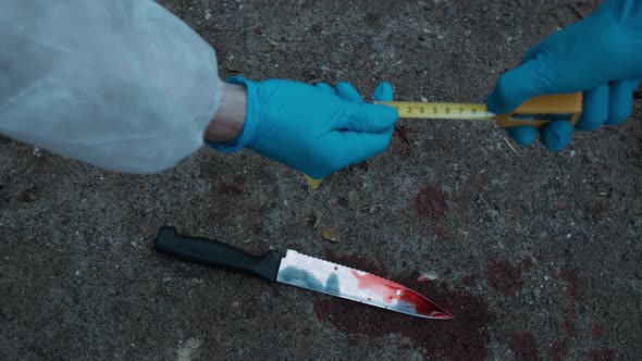 Criminalists Discovering Knife at Crime Scene Measuring Crime Scene Closeup Taking Evidence From