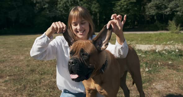 Happy Young Female Cheerfully Playing Sitting with Dog in the Lawn. Love and Friendship