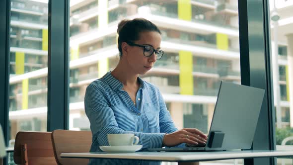 Cafe and a Woman Working on a Laptop in It