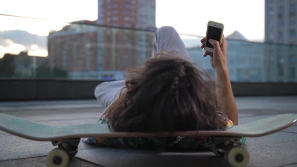 Skater Surfing on Phone Lying with Head on Board