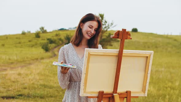 Young Smiling Woman Drawing a Painting on Nature
