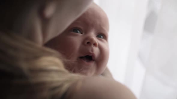 Close Portrait of Crying Newborn Baby in Mother Embraces