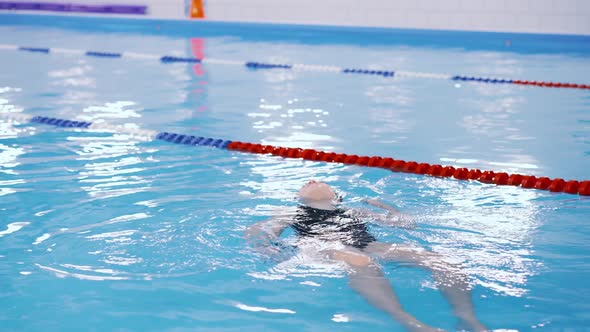 Swimming Lessons for Children in the Pool - Beautiful Fair-skinned Girl Swims in the Water