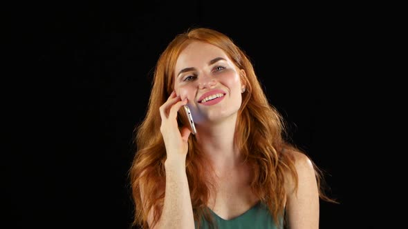 Redhaired Girl Talking on the Phone. Black Background