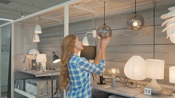 Rear View Shot of a Female Customer Choosing Lamps at Furniture Store