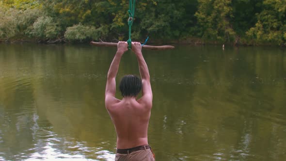 Young Man Swings on the Stick and Falling Down in the River