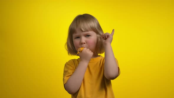A Cute Little Girl is Blowing in a Whistle and Making a No Gesture in a Camera