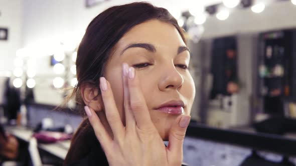 Process of Make Up Artist's Hand Applying Foundation on Previously Prepared Face of an Attractive
