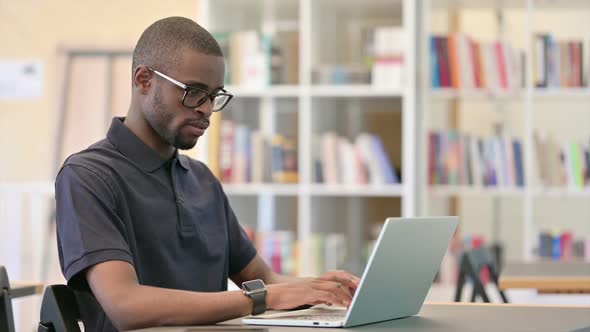 Focused Young African Man Working on Laptop in Library