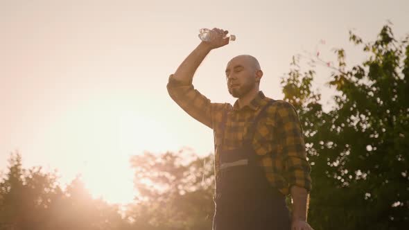 Caucasian bald bearded man takes off his straw hat and pours water from a bottle over his head