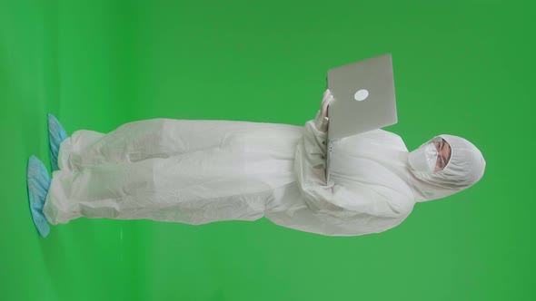 Asian Man Wear Protective Uniform Ppe Holding And Working With Laptop In The Green Screen Studio