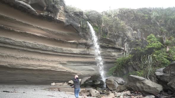 Female traveler walking near waterfall cliff