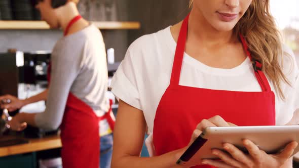 Waitress using digital tablet at counter