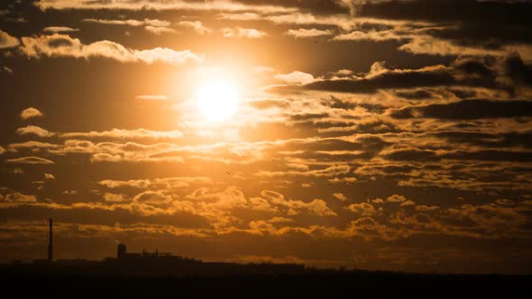 Dramatic Sunset Over the Storm Clouds and Over Trees and Pipes of the Plant. Time Lapse