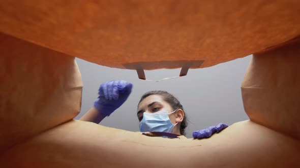 Woman in Gloves and Mask with Food in Paper Bag