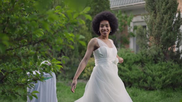 Cheerful Happy Young African American Woman in Wedding Dress Spinning Looking at Camera