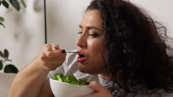 Smiling Young Woman Eating Vegetable Salad at Home