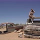 Young Woman in Safari Overalls Sits on the Rooftop of Abandoned Old Rusty Car - VideoHive Item for Sale