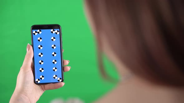 Lady Holds the Phone Hand and Scrolls Finger Down Chromakey Phone Screen to Track and Insert Video