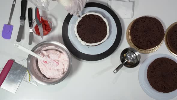 Front Shot of a Baker Using an Icing Spatula to Carefully Touch Up Sides of Cream Covered Cake