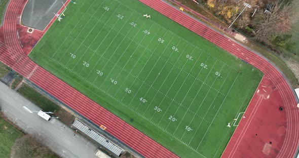 Top down aerial of football field and track field stadium at school college university campus.