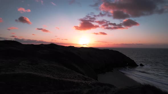 AERIAL: Slow pan over coastal cliffs towards sunset, Blue Pool Bay, 4k Drone