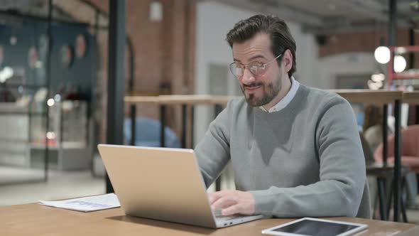 Young Man Celebrating Success While Using Laptop in Office