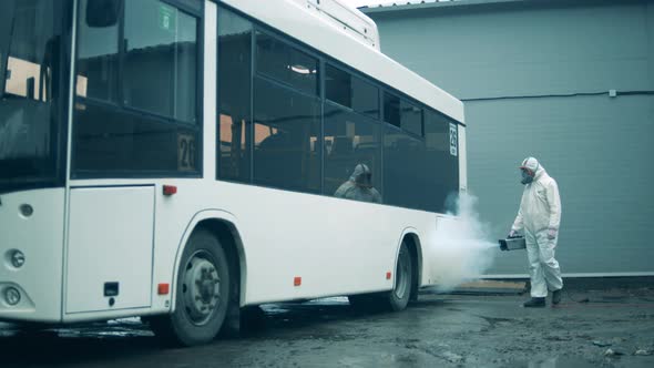 Man Sanitizes a White Bus To Kill Virus