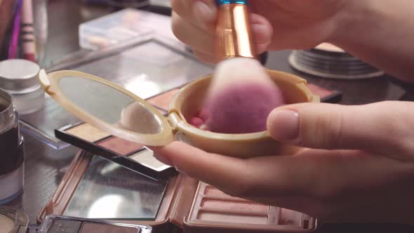 Makeup Brush Applying Cosmetic Powder Balls on Vanity Table Close Up