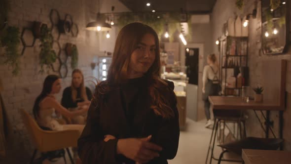 A Spectacular Young Girl in Black Clothes is Standing in the Lobby of a Stylish Cafe and
