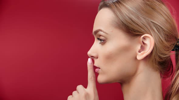 Closeup Adorable Young Female Keeping Secret Putting Forefinger to Lips Side View